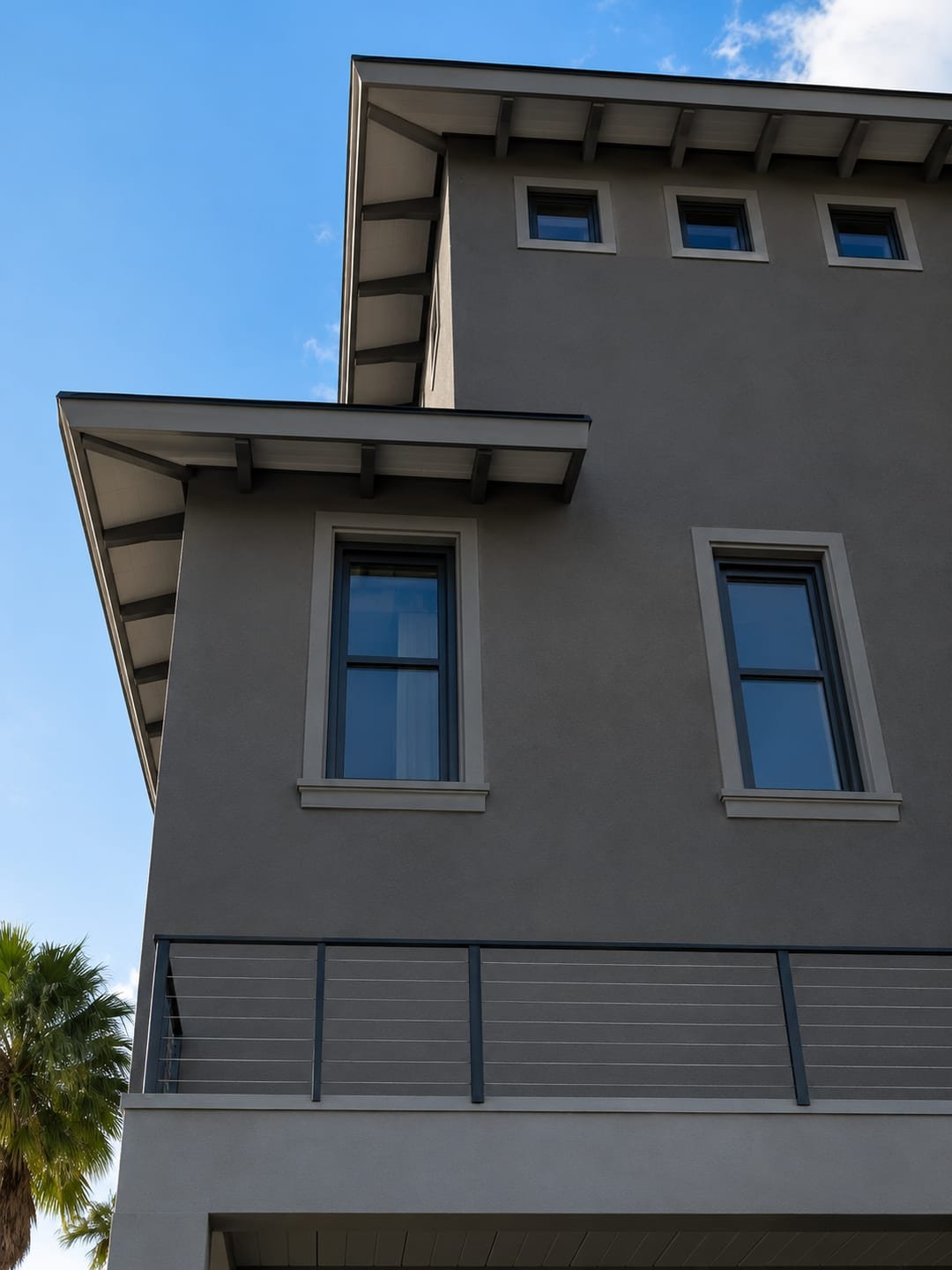 The same elevation finished by Acosta Builders — windows set square in trimmed stucco openings with sills, under wrapped eaves