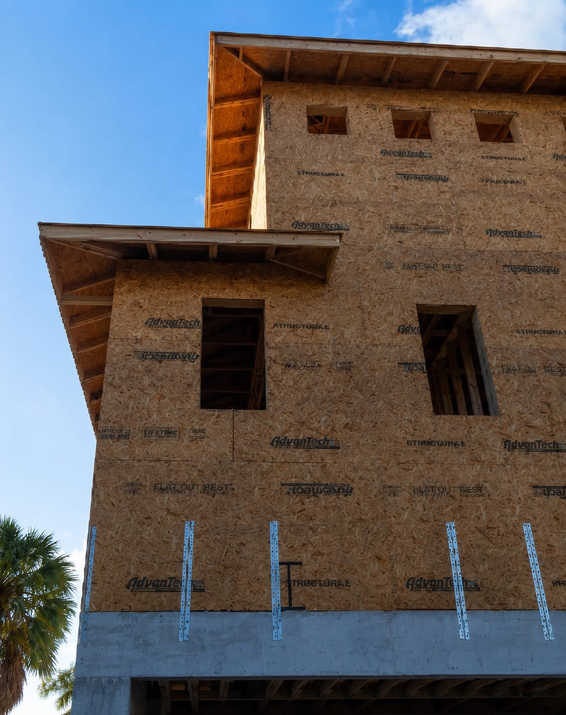 Framed window openings by Acosta Builders in a sheathed three-storey wall, with stacked eaves and exposed rafter tails before the units go in