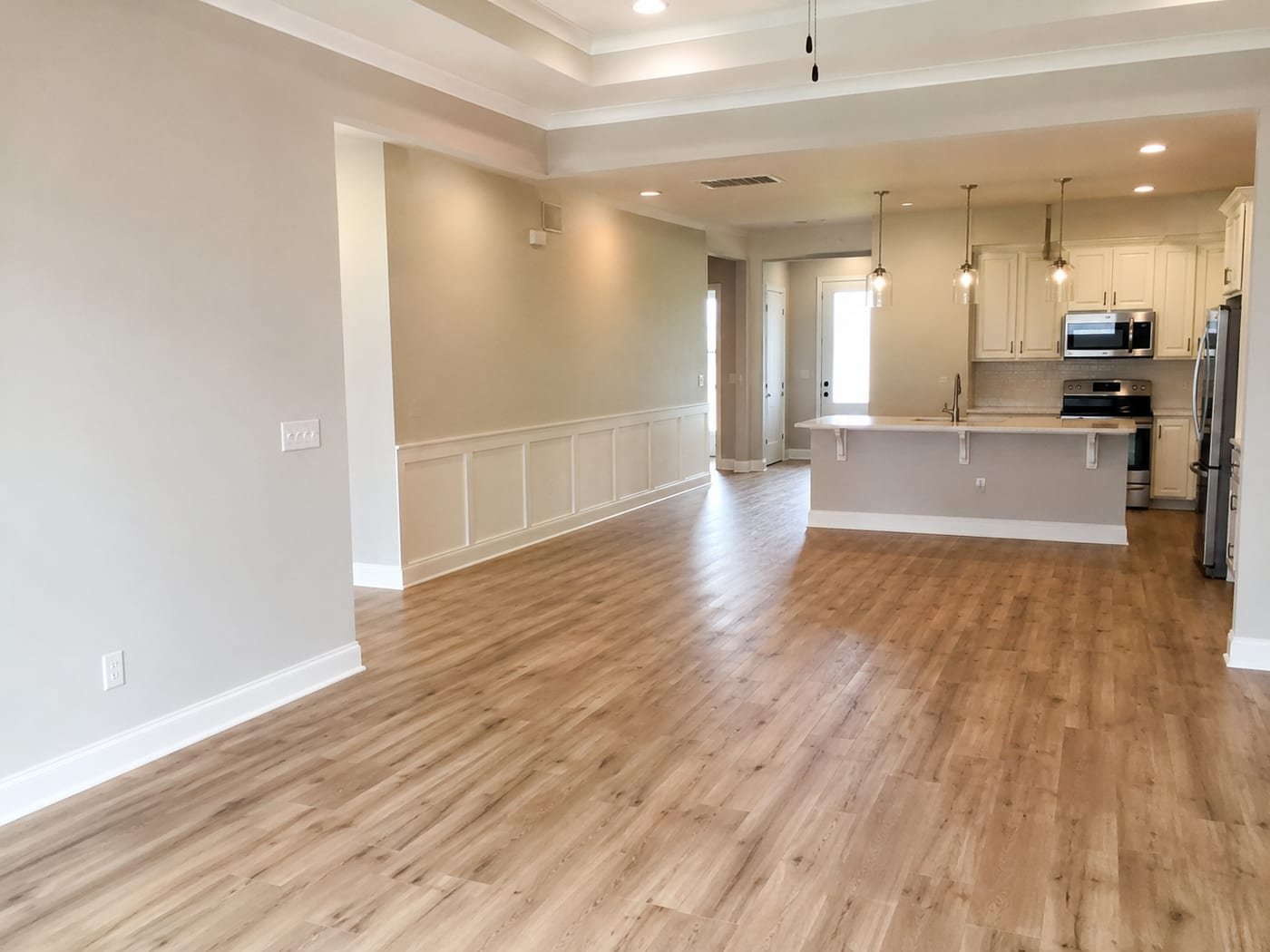 Interior finishes by Acosta Builders — wide-plank flooring, panelled wainscot, baseboard, and a coffered tray ceiling