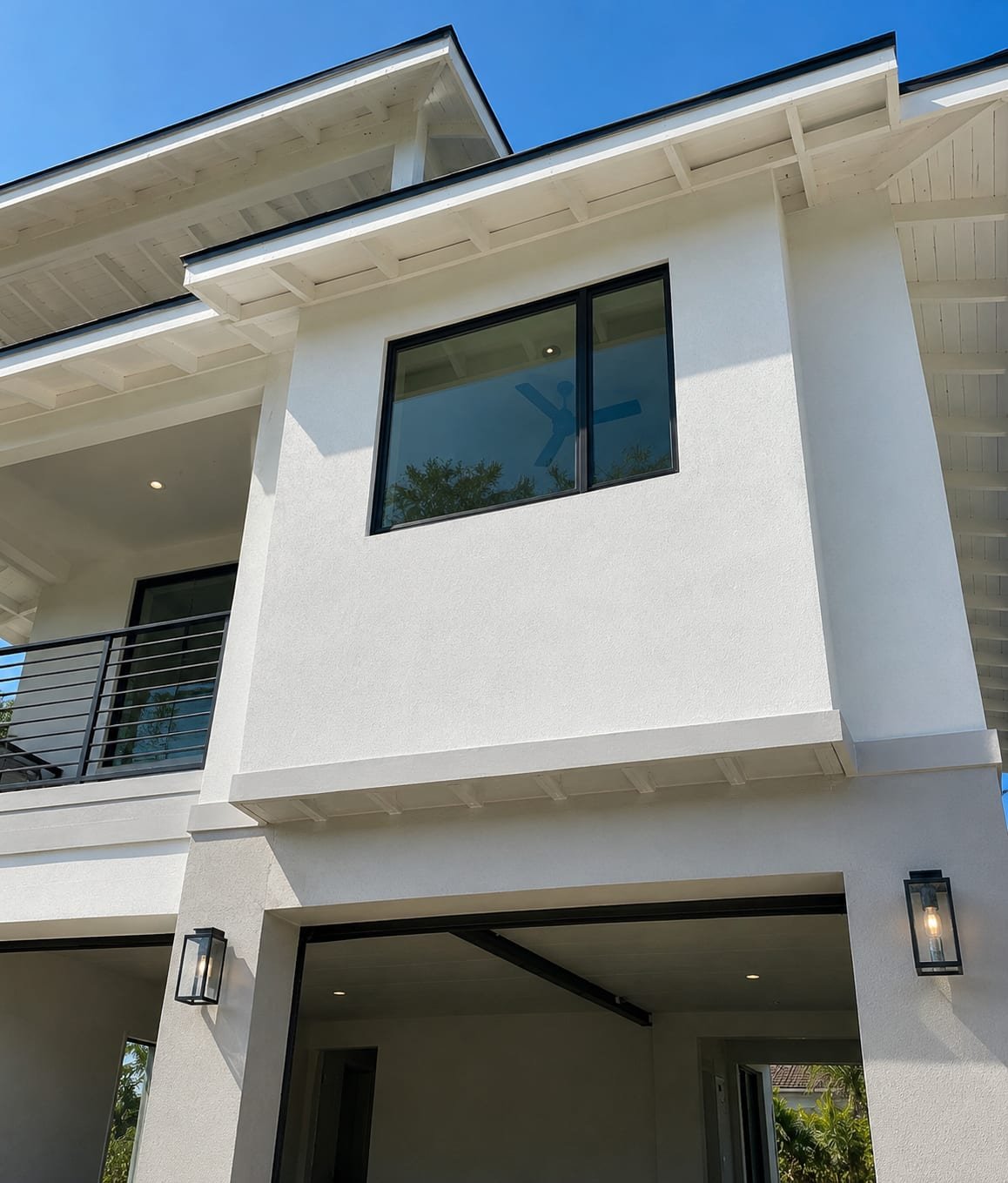 Energy-efficient glazing by Acosta Builders — a Low-E unit shaded by a deep overhanging eave and wood soffit on a Gulf Coast elevation