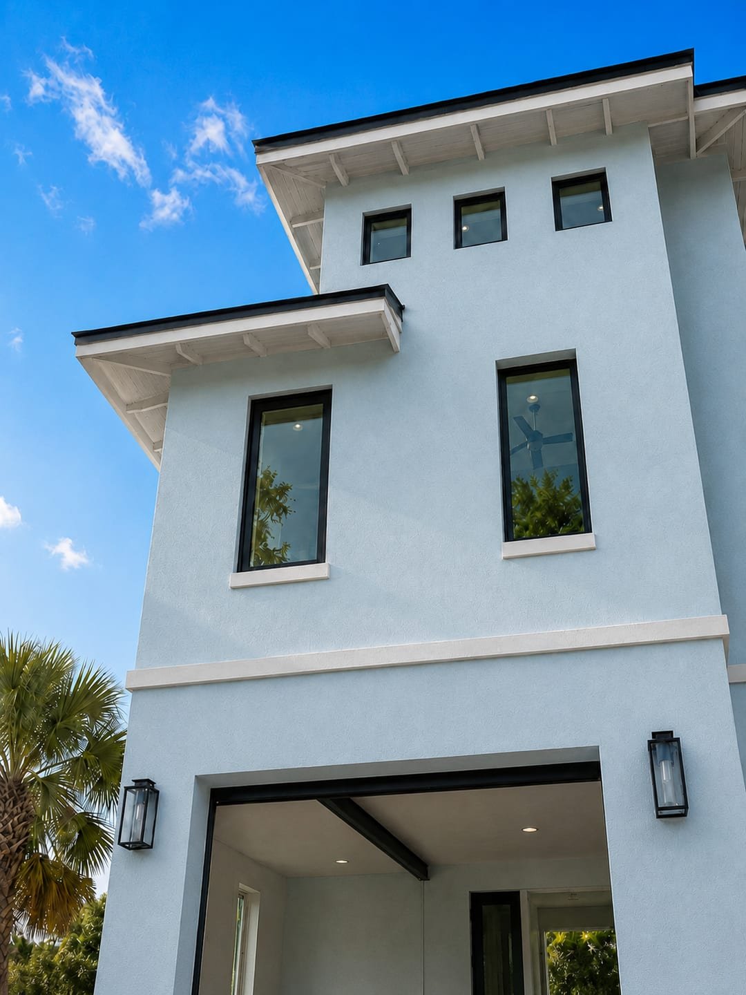 Impact-rated windows installed by Acosta Builders — black-framed units set with trimmed sills across a stucco elevation under deep eaves